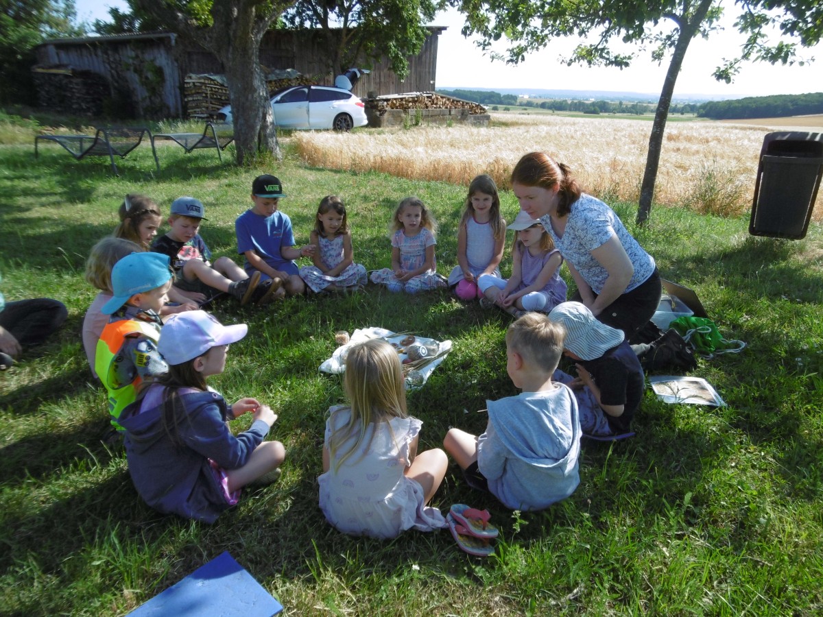 Kinder sitzen auf einer Wiese in einem Kreis